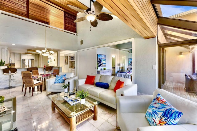 living area featuring a textured wall, a high ceiling, and ceiling fan with notable chandelier