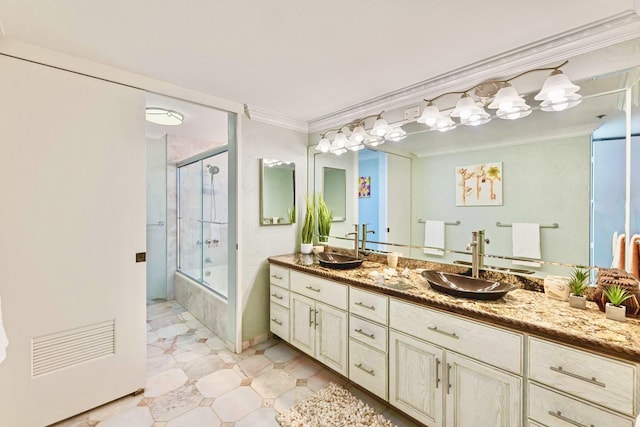 bathroom with enclosed tub / shower combo, ornamental molding, a sink, and double vanity