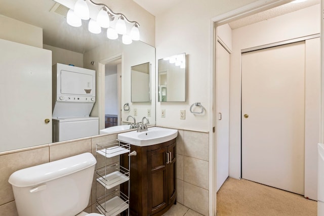 140 Uwapo Rd Unit 18-203, Kihei, HI 96753 - bathroom featuring stacked washer and clothes dryer, tile walls, vanity, and wainscoting
