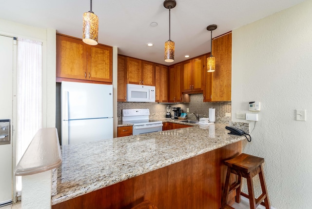 kitchen featuring light stone counters, kitchen peninsula, white appliances, a breakfast bar area, and decorative backsplash