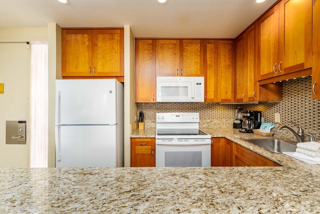 kitchen featuring light stone counters, sink, white appliances, and decorative backsplash