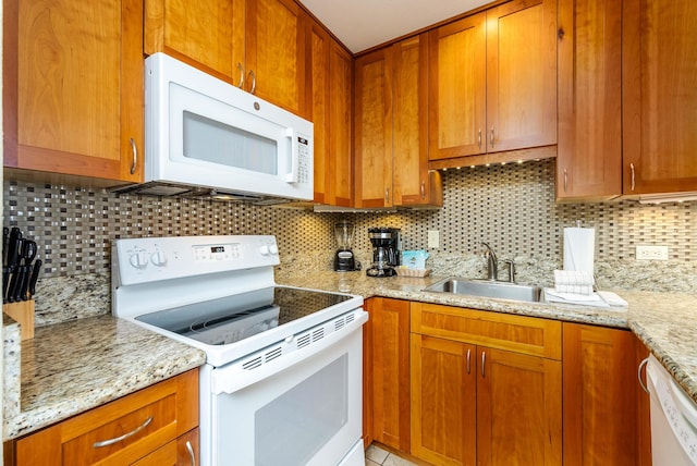 kitchen featuring light stone counters, white appliances, sink, and tasteful backsplash