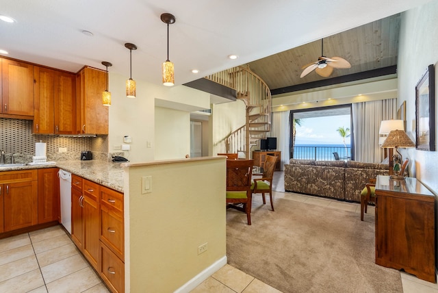 kitchen with light stone countertops, ceiling fan, light carpet, kitchen peninsula, and decorative light fixtures