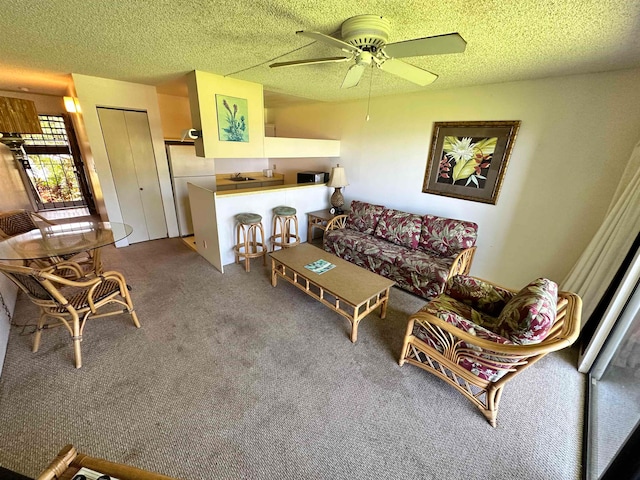 living room featuring carpet floors, ceiling fan, and a textured ceiling