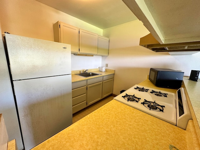 kitchen with sink, white fridge, and range hood