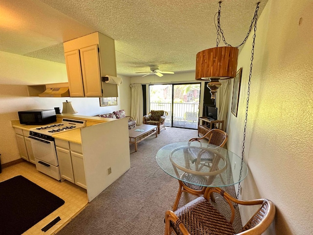 kitchen featuring white gas stove, ceiling fan, custom range hood, light colored carpet, and a textured ceiling