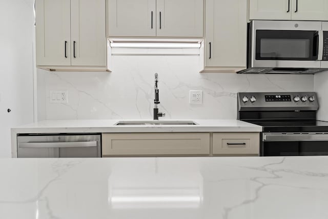 kitchen with light stone counters, tasteful backsplash, appliances with stainless steel finishes, and a sink