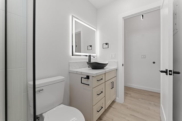 bathroom with toilet, vanity, baseboards, and wood finished floors