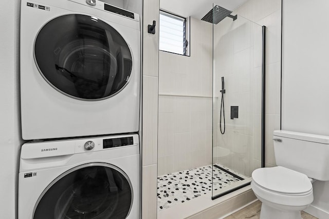 clothes washing area featuring stacked washer and dryer, wood finished floors, and laundry area