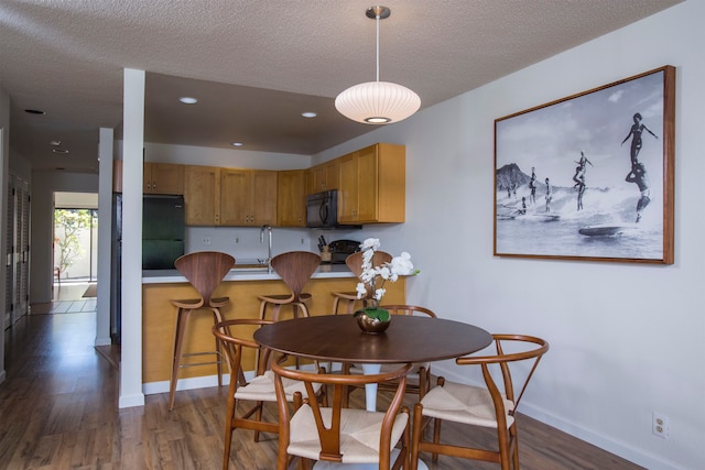 dining space with hardwood / wood-style flooring and a textured ceiling