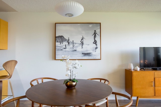 dining area with a textured ceiling and dark wood-type flooring