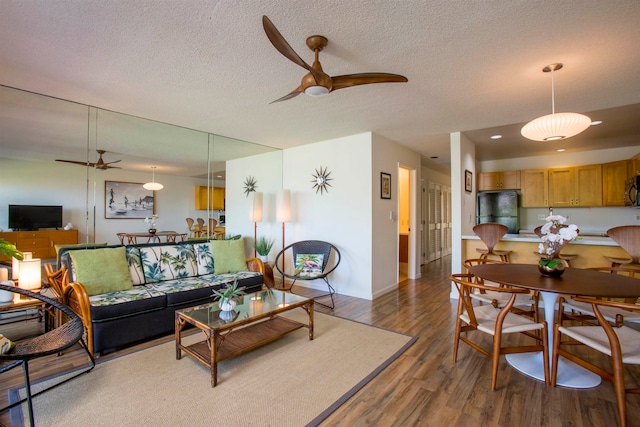 living room with a textured ceiling, ceiling fan, and hardwood / wood-style flooring