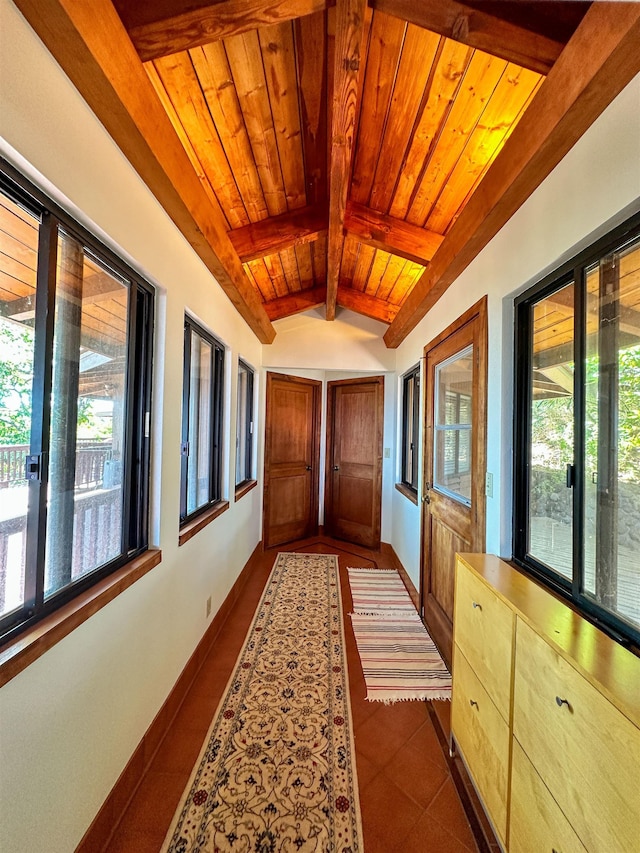 hall featuring vaulted ceiling with beams, dark tile patterned flooring, and wooden ceiling