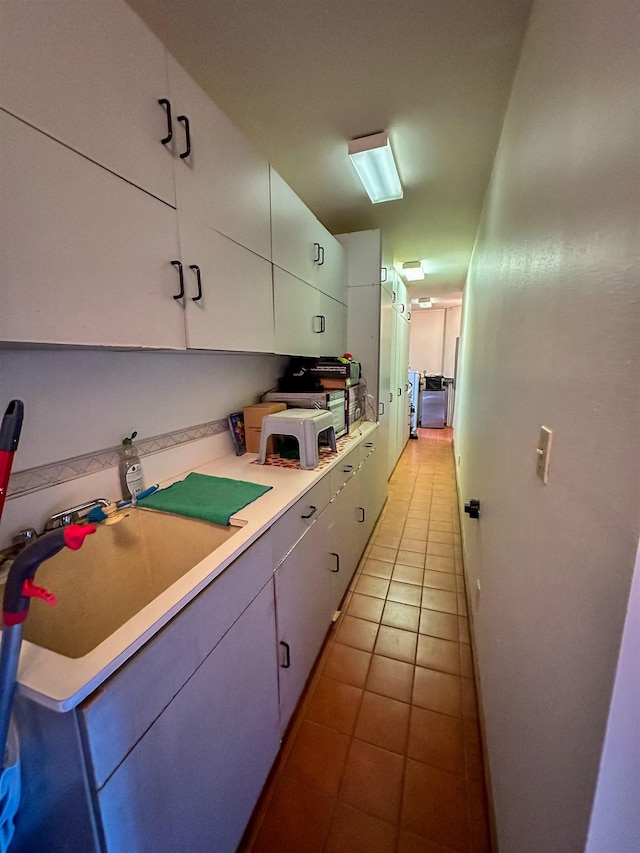 kitchen with sink, light tile patterned floors, and white cabinets