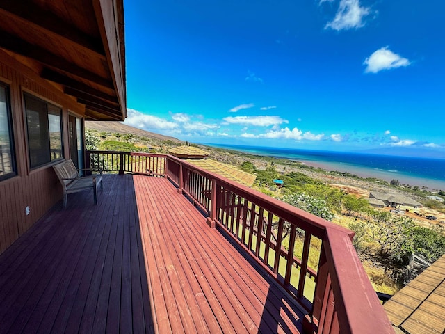 wooden terrace featuring a beach view and a water view