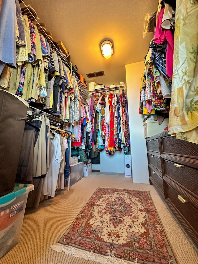 walk in closet with light carpet