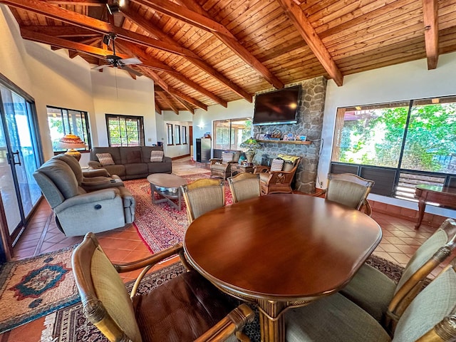 dining area featuring high vaulted ceiling, a fireplace, beamed ceiling, wood ceiling, and tile patterned floors