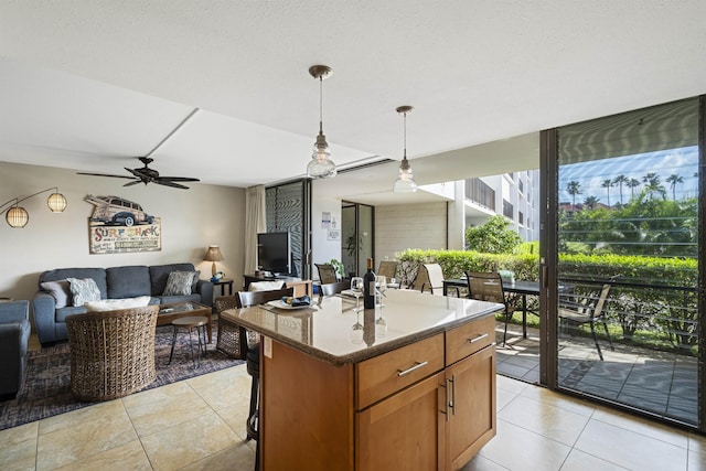 kitchen featuring brown cabinets, open floor plan, dark stone countertops, hanging light fixtures, and a center island