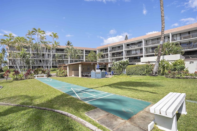 view of property's community with shuffleboard and a yard