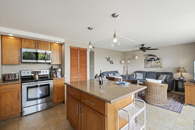 kitchen with appliances with stainless steel finishes, stone counters, brown cabinets, and open floor plan