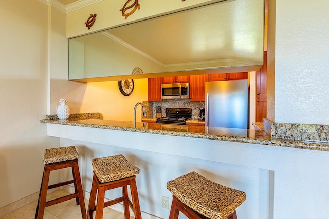 kitchen with stone counters, crown molding, a kitchen bar, and stainless steel appliances