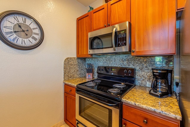 kitchen featuring light stone countertops, decorative backsplash, and black / electric stove