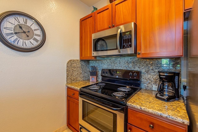 155 Wailea Ike Pl Unit 67, Kihei, HI 96753 - kitchen featuring appliances with stainless steel finishes, light stone counters, brown cabinetry, and backsplash