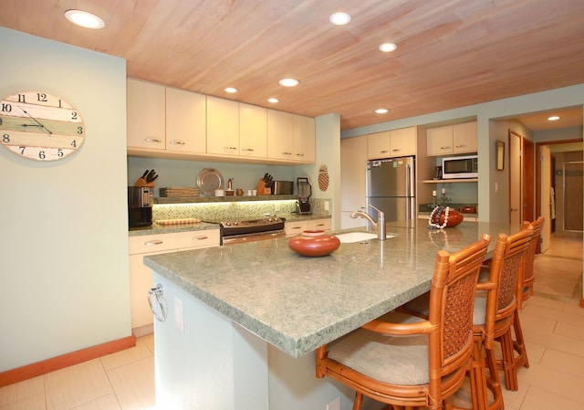 kitchen with wooden ceiling, appliances with stainless steel finishes, light tile flooring, and an island with sink