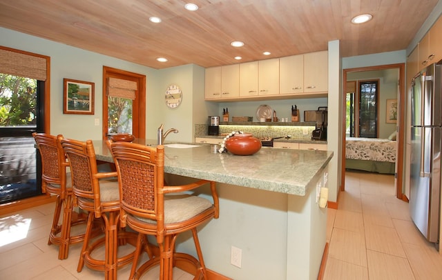 kitchen with wood ceiling, high end refrigerator, white cabinets, and sink