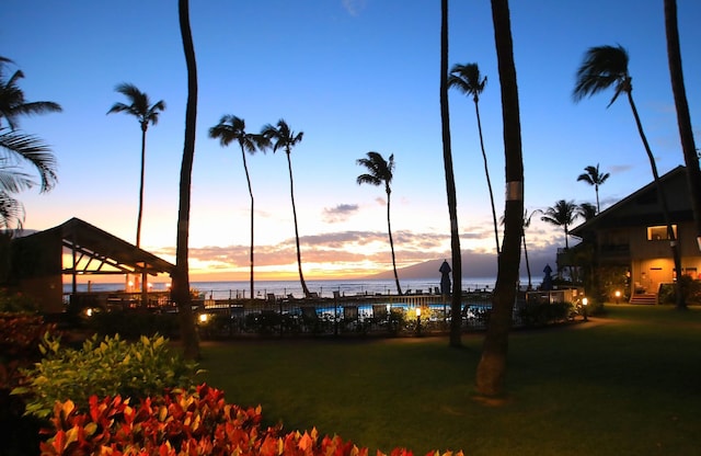 yard at dusk featuring a water view