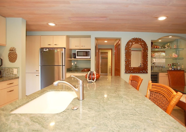 kitchen with beverage cooler, cream cabinets, appliances with stainless steel finishes, sink, and wooden ceiling