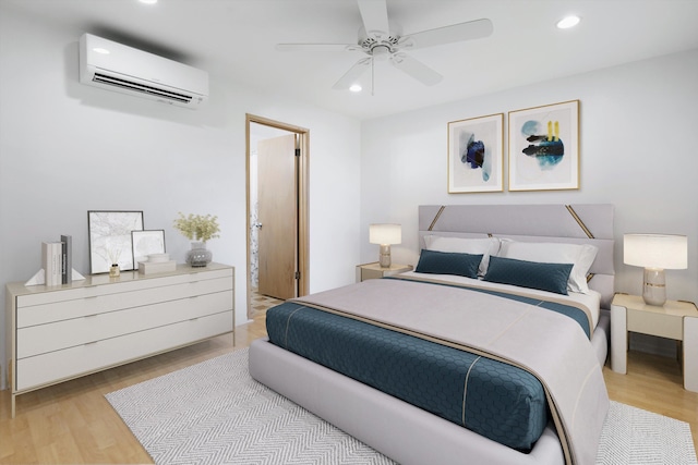 bedroom featuring light hardwood / wood-style flooring, ceiling fan, ensuite bath, and a wall mounted air conditioner