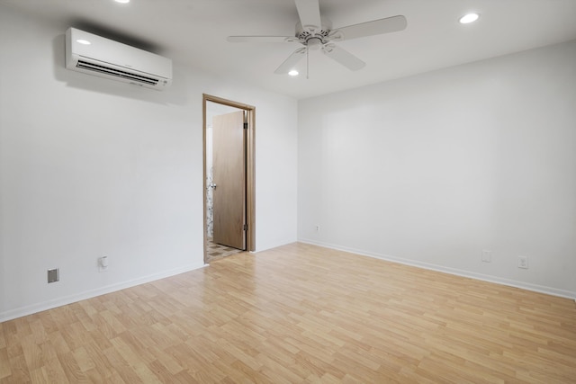 spare room with ceiling fan, a wall mounted air conditioner, and light hardwood / wood-style flooring