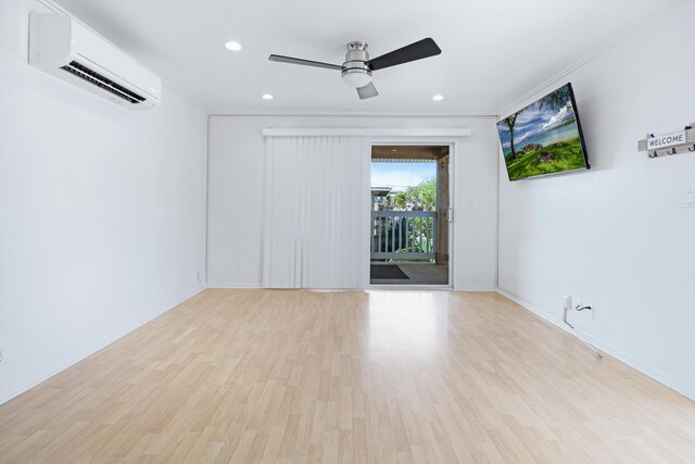 spare room with ceiling fan, a wall unit AC, and light hardwood / wood-style floors