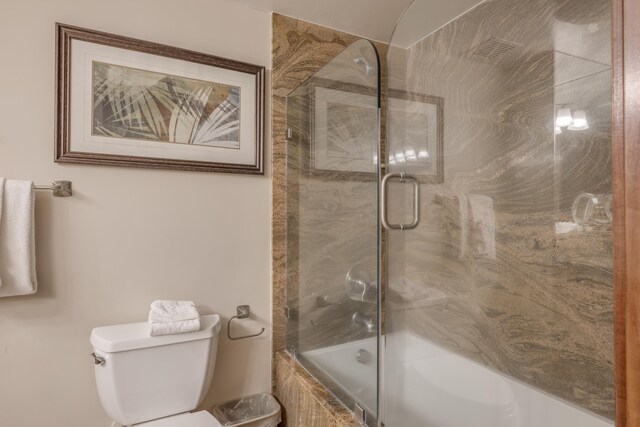 bathroom featuring bath / shower combo with glass door and toilet