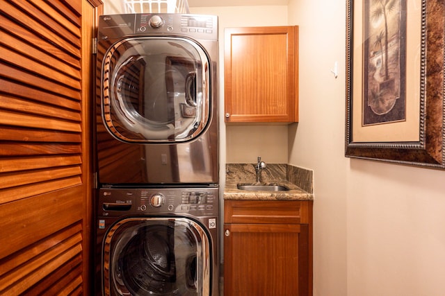 washroom featuring stacked washer and clothes dryer, sink, and cabinets