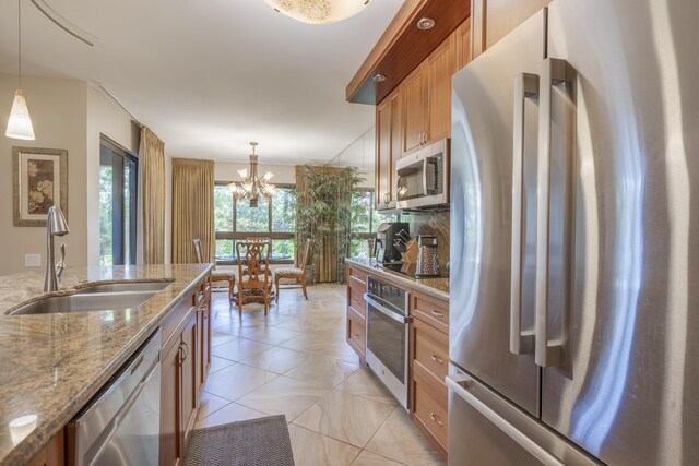 kitchen with an inviting chandelier, sink, pendant lighting, and stainless steel appliances