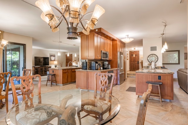 kitchen with kitchen peninsula, appliances with stainless steel finishes, decorative light fixtures, and sink