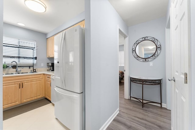 kitchen with light hardwood / wood-style flooring, white appliances, sink, and light brown cabinetry