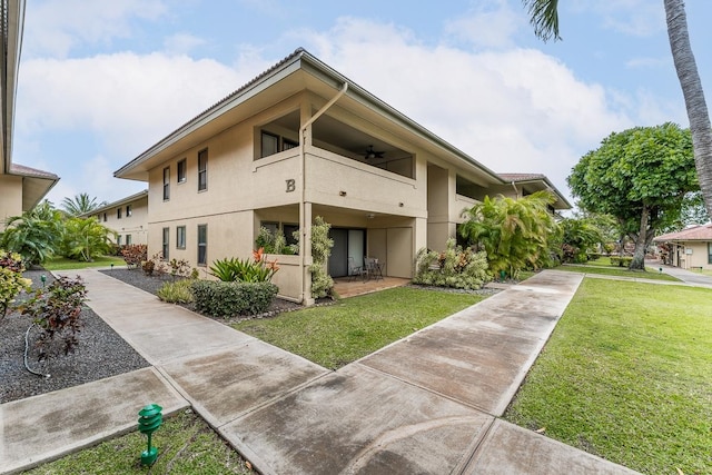 exterior space with ceiling fan and a front lawn