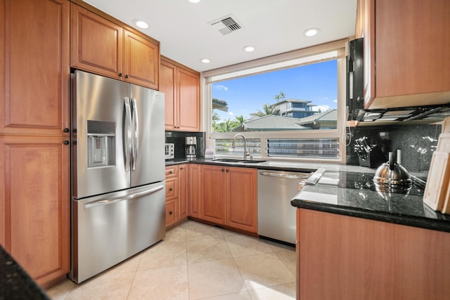 kitchen featuring sink, dark stone countertops, light tile patterned floors, tasteful backsplash, and stainless steel appliances