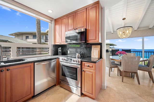 kitchen with stainless steel appliances, sink, a water view, a chandelier, and hanging light fixtures