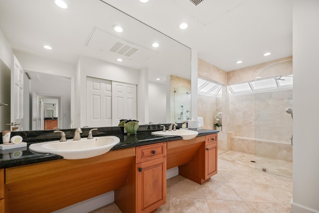 bathroom with tile patterned flooring, vanity, and tiled shower