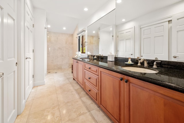 bathroom with tiled shower, vanity, and tile patterned flooring