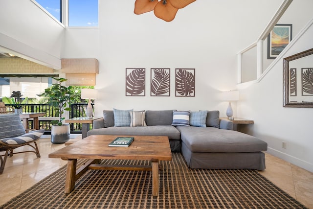 living room featuring a towering ceiling, tile patterned floors, plenty of natural light, and ceiling fan