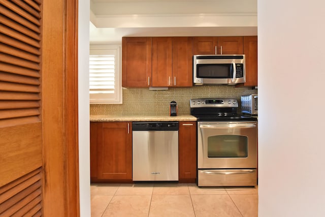 kitchen featuring backsplash, appliances with stainless steel finishes, light tile floors, and light stone countertops