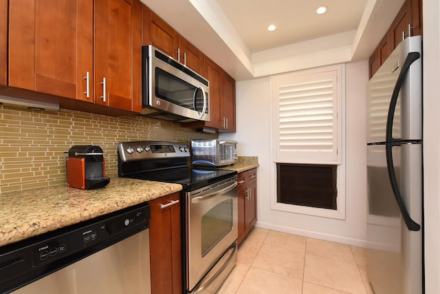 kitchen with appliances with stainless steel finishes, tasteful backsplash, light stone countertops, and light tile flooring