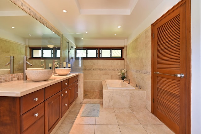 bathroom with tile walls, a raised ceiling, independent shower and bath, tile flooring, and vanity