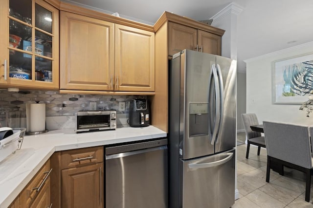 kitchen featuring light stone countertops, stainless steel appliances, backsplash, light tile patterned floors, and crown molding