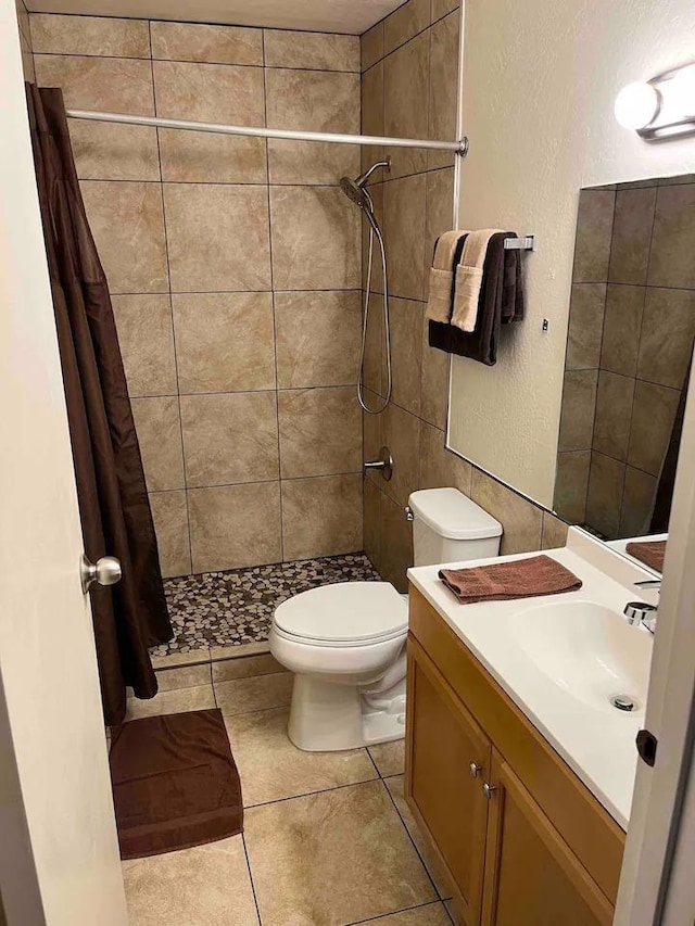 bathroom with curtained shower, toilet, tile floors, and vanity with extensive cabinet space